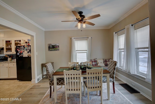 dining area with baseboards, light wood-style flooring, visible vents, and crown molding