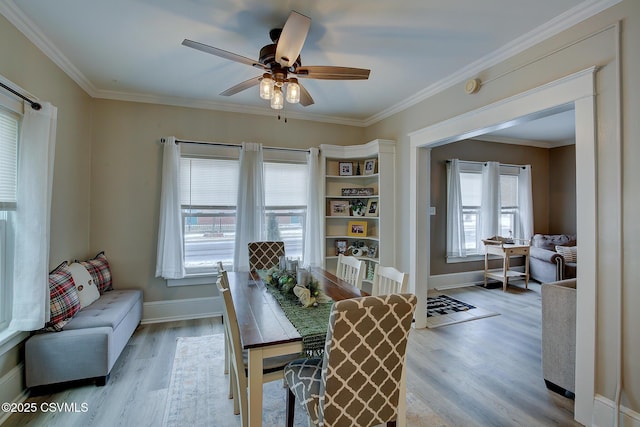 dining area with light wood-style floors, ceiling fan, baseboards, and crown molding