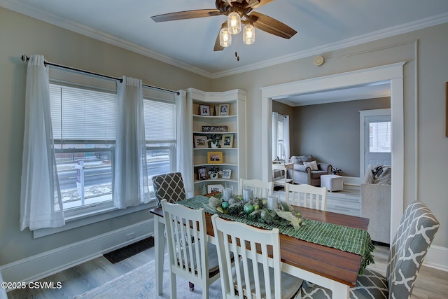 dining room with light wood-style floors, visible vents, crown molding, and baseboards