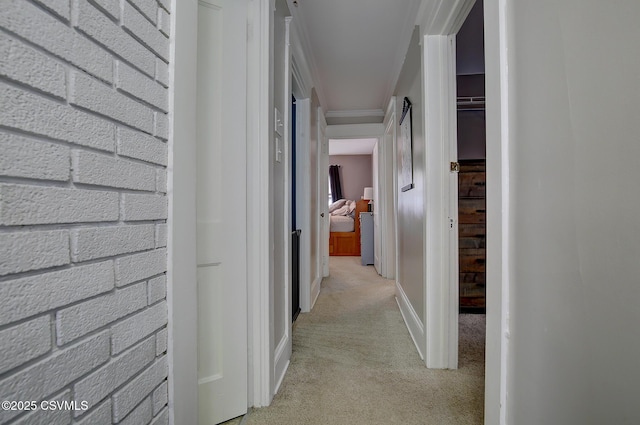 hallway featuring crown molding and light colored carpet