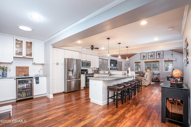 kitchen with beverage cooler, appliances with stainless steel finishes, open floor plan, and white cabinetry