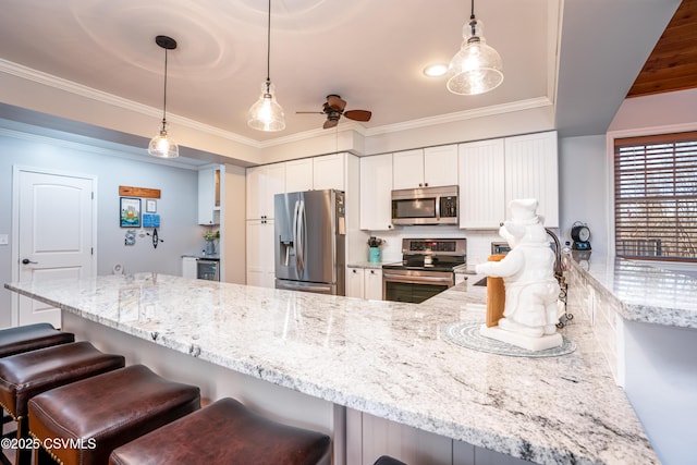 kitchen with appliances with stainless steel finishes, white cabinetry, hanging light fixtures, and light stone countertops