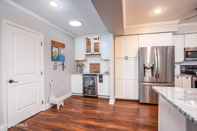 kitchen with white cabinets, wine cooler, glass insert cabinets, appliances with stainless steel finishes, and light stone counters