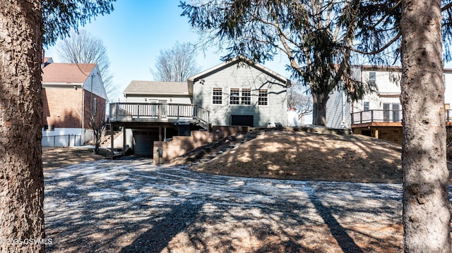 back of house featuring a garage, driveway, stairway, and a wooden deck