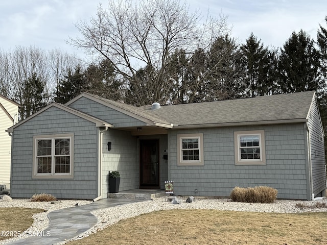 ranch-style house featuring a front lawn and roof with shingles