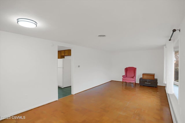 unfurnished room with light wood finished floors and a baseboard heating unit