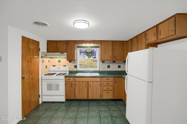 kitchen with white appliances, a sink, visible vents, backsplash, and dark countertops