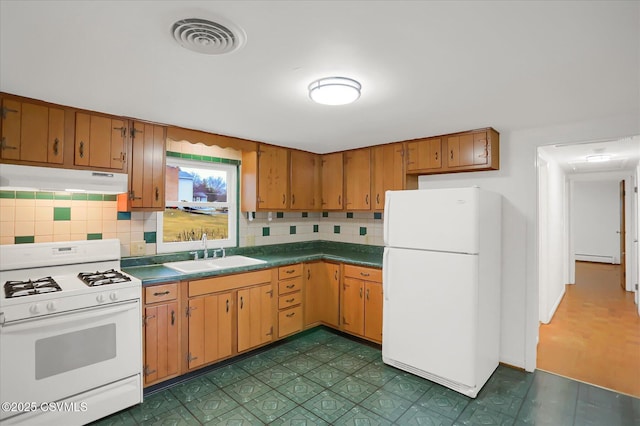 kitchen featuring under cabinet range hood, white appliances, a sink, visible vents, and tasteful backsplash