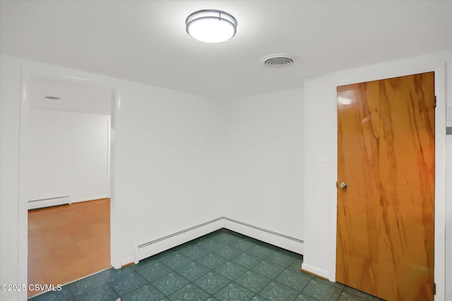 spare room featuring a baseboard radiator, visible vents, and dark floors