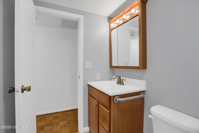 bathroom featuring toilet, visible vents, baseboards, and vanity