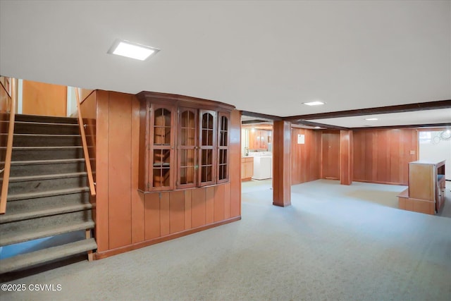 basement featuring stairs, washer / clothes dryer, wood walls, and carpet