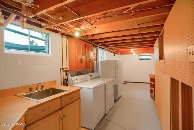 clothes washing area with a wealth of natural light, separate washer and dryer, a sink, and cabinet space