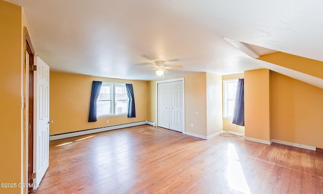 interior space with a closet, a baseboard heating unit, light wood-style floors, a ceiling fan, and baseboards