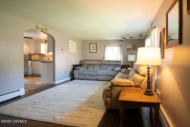 living area with a baseboard heating unit, wood finished floors, arched walkways, and baseboards