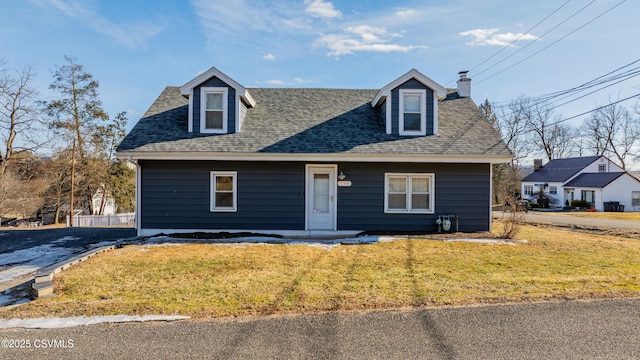 view of front of property with roof with shingles, a chimney, and a front lawn