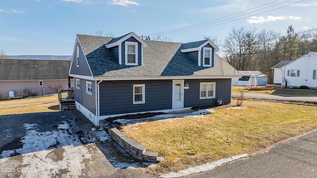 view of front facade with roof with shingles and a front yard