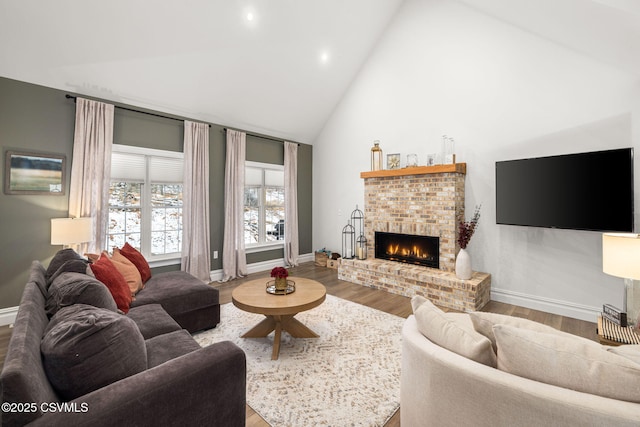 living room featuring wood-type flooring, high vaulted ceiling, and a brick fireplace