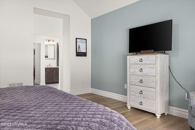 bedroom with dark hardwood / wood-style flooring, connected bathroom, and vaulted ceiling