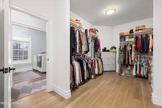 spacious closet with washer and dryer and light hardwood / wood-style flooring