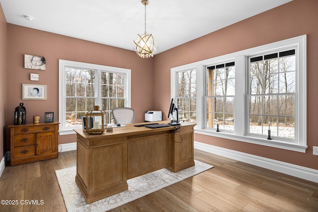 home office with an inviting chandelier and light hardwood / wood-style floors