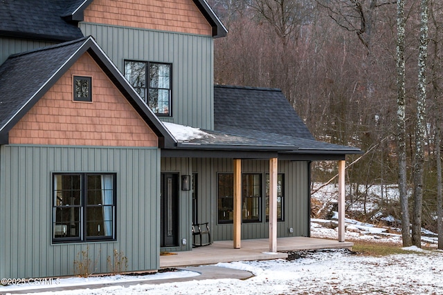 snow covered rear of property with a porch