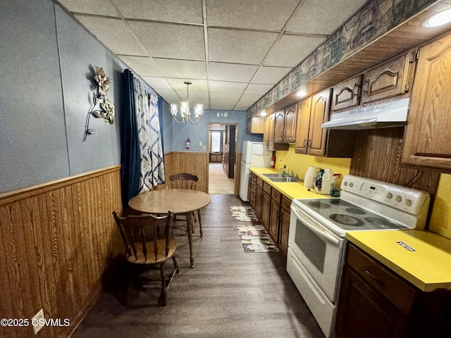 kitchen with dark wood-type flooring, sink, hanging light fixtures, white appliances, and a drop ceiling