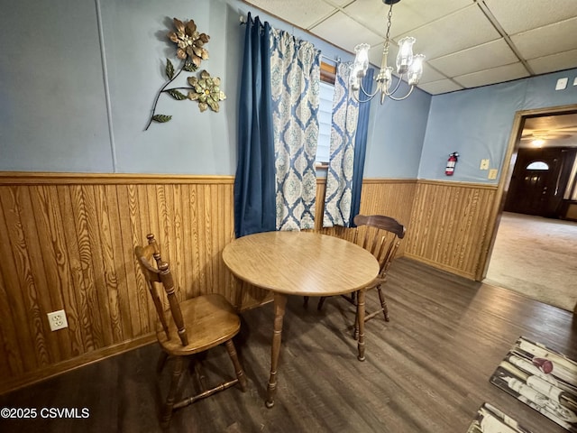 dining space featuring hardwood / wood-style floors, a notable chandelier, a paneled ceiling, and wooden walls