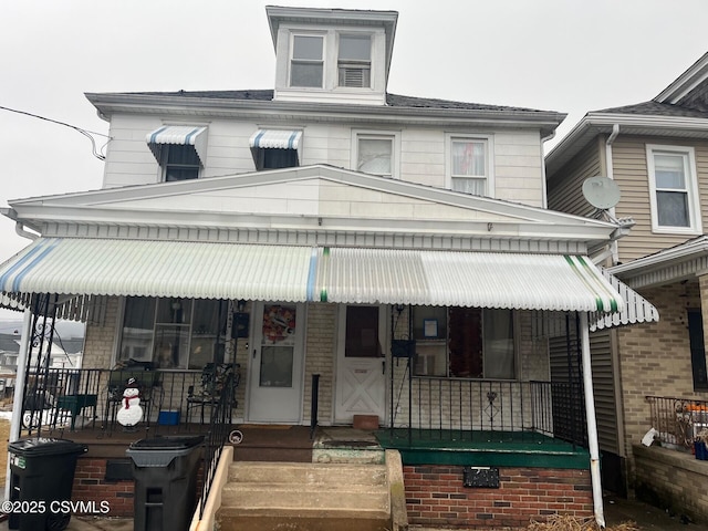 american foursquare style home featuring covered porch and brick siding