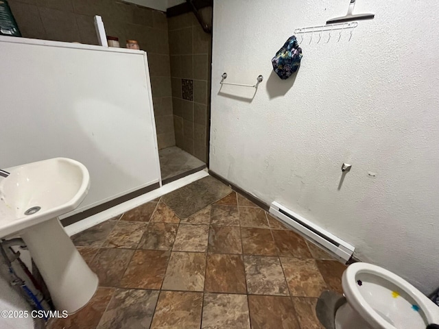 bathroom featuring a baseboard heating unit, stone finish floor, toilet, and baseboards