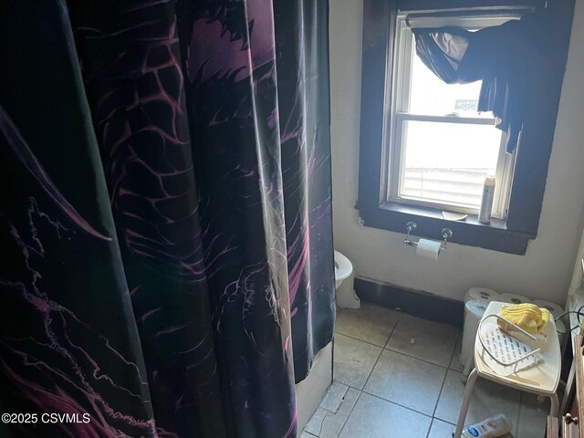 bathroom with toilet, curtained shower, and tile patterned flooring