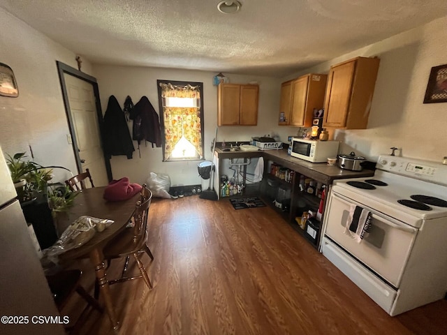 kitchen featuring dark wood-style flooring, dark countertops, brown cabinetry, a textured ceiling, and white appliances