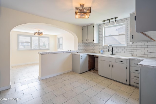 1041 Pine St, Kulpmont, PA 17834 - kitchen featuring arched walkways, decorative backsplash, light countertops, light tile patterned floors, and a peninsula