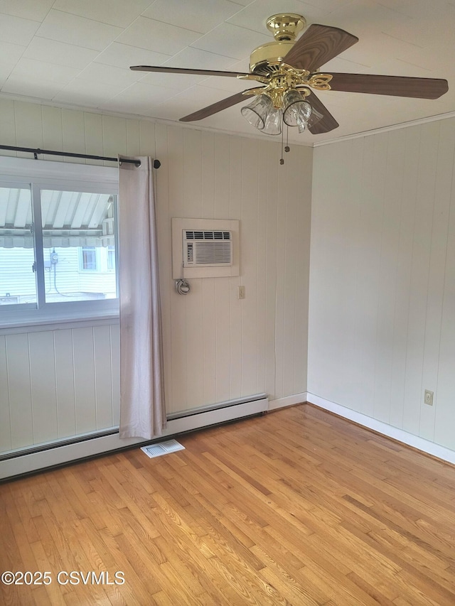 spare room featuring a ceiling fan, light wood-type flooring, baseboards, and a wall mounted AC