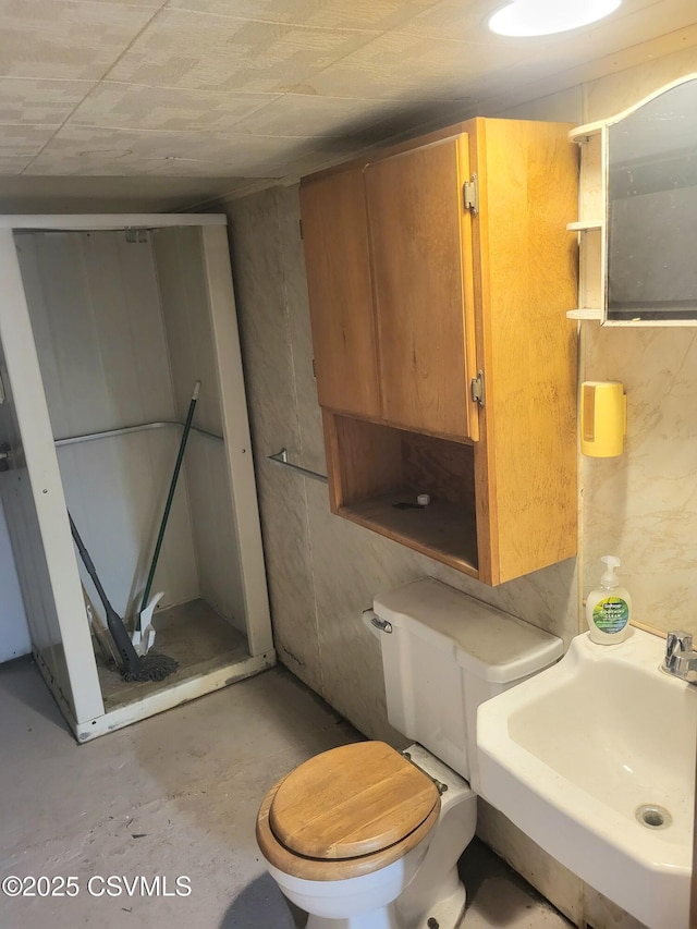 bathroom with concrete floors, a sink, and toilet