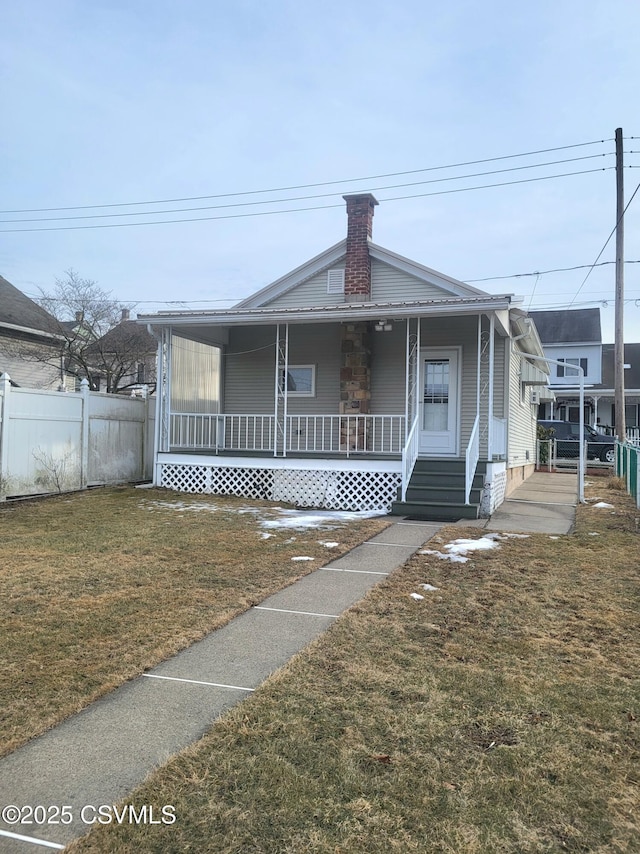 view of front of home with covered porch, fence, metal roof, and a front yard