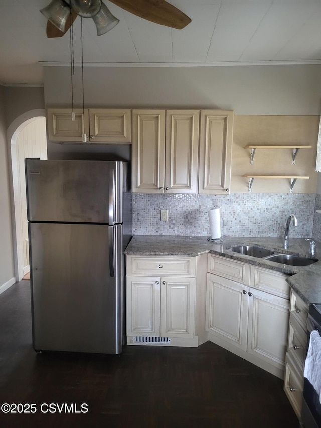 kitchen with light stone counters, open shelves, decorative backsplash, appliances with stainless steel finishes, and a sink