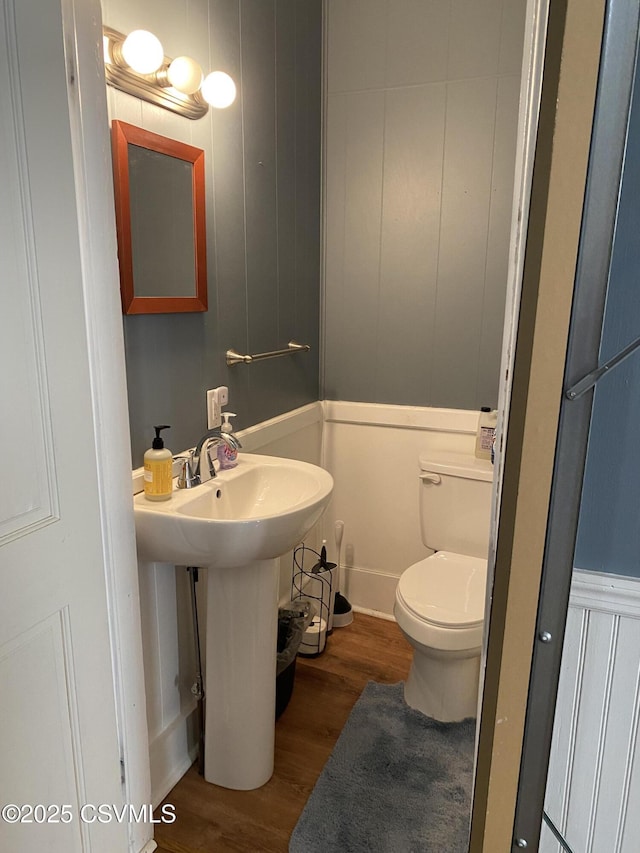 bathroom with toilet, a sink, and wood finished floors