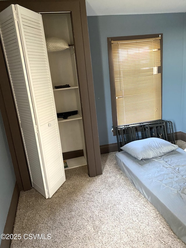 carpeted bedroom featuring a closet and baseboards