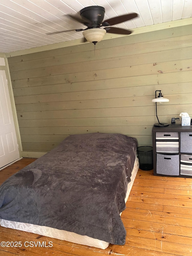 bedroom featuring a ceiling fan, light wood-type flooring, wood ceiling, and wooden walls