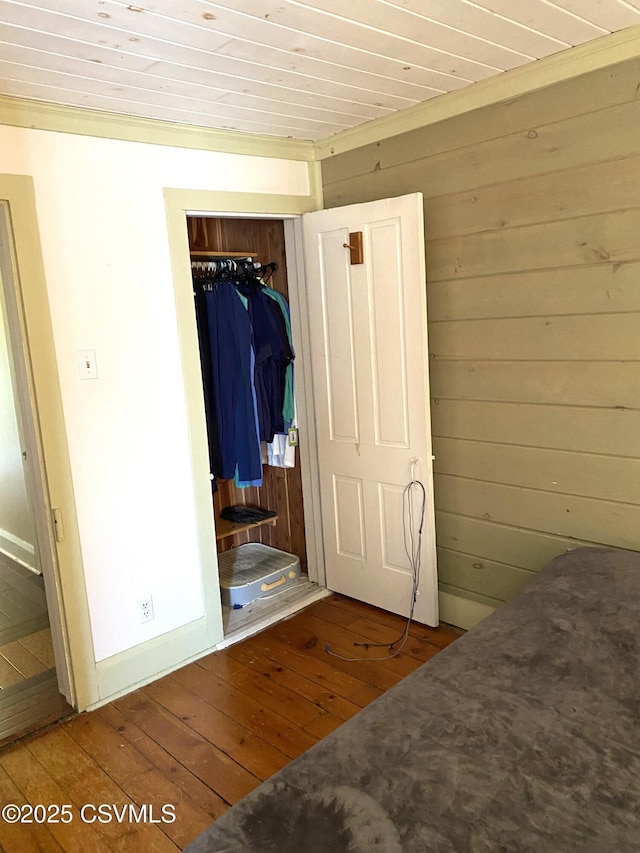 bedroom with hardwood / wood-style floors, wood walls, a closet, and wood ceiling