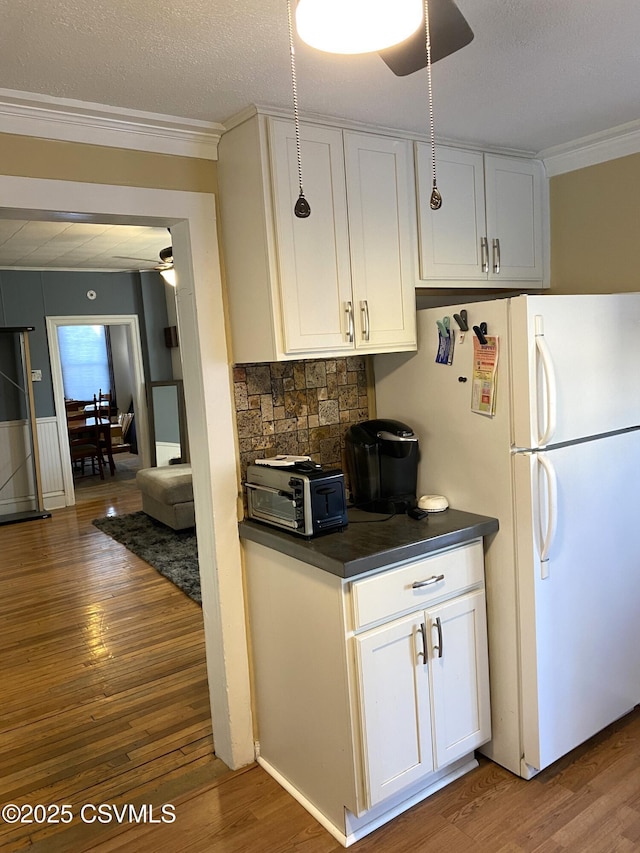 kitchen with dark countertops, crown molding, ceiling fan, and wood finished floors