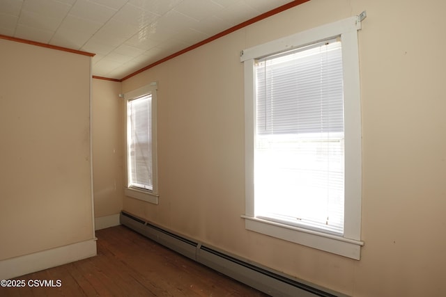 empty room featuring ornamental molding, a baseboard heating unit, and hardwood / wood-style floors