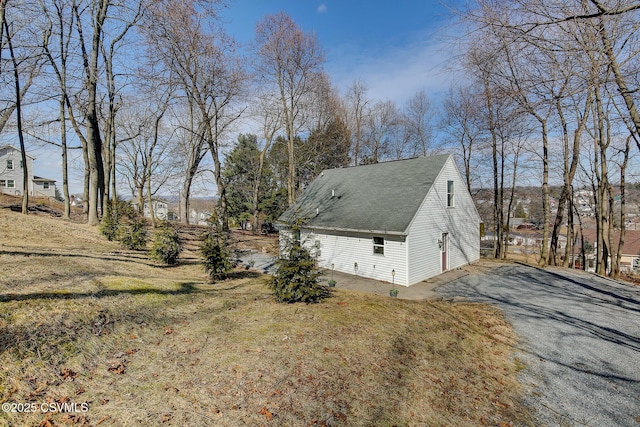 view of home's exterior featuring aphalt driveway and a shingled roof