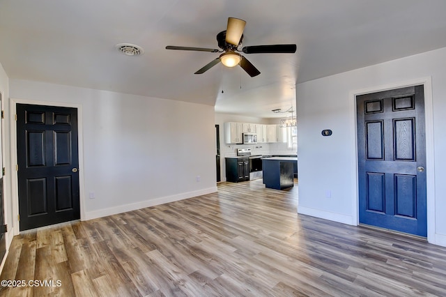 unfurnished living room featuring light wood-style floors, visible vents, baseboards, and a ceiling fan