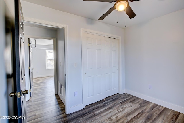 unfurnished bedroom with ceiling fan, a closet, wood finished floors, and baseboards