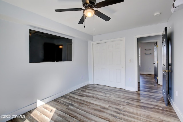 unfurnished bedroom featuring ceiling fan, a closet, wood finished floors, and baseboards