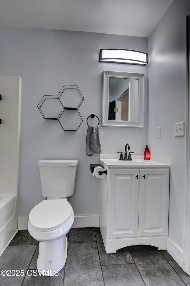 full bathroom featuring a tub to relax in, baseboards, vanity, and toilet