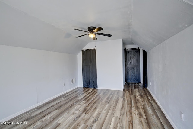 additional living space with lofted ceiling, visible vents, ceiling fan, wood finished floors, and baseboards