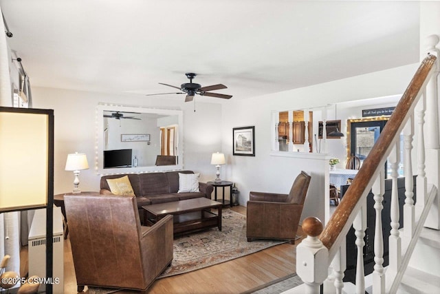 living area with a ceiling fan, stairway, and wood finished floors