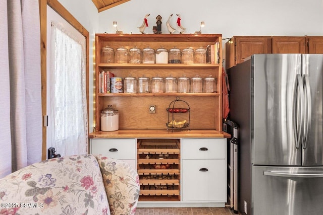 interior space with lofted ceiling, light countertops, freestanding refrigerator, brown cabinets, and open shelves